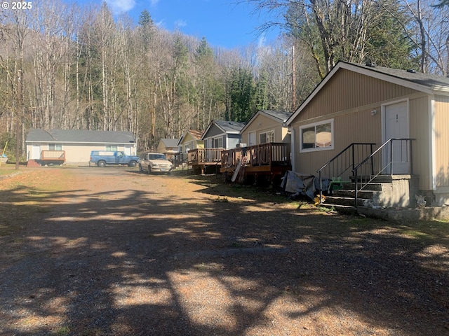 view of yard with a wooden deck and a view of trees