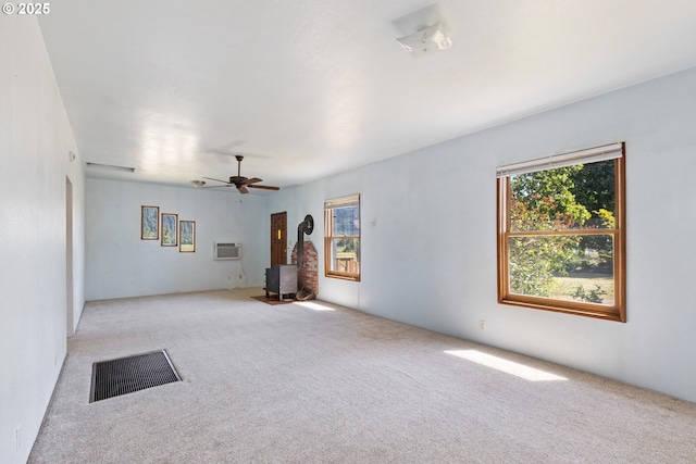2170 Hubbard Creek Rd, Umpqua, OR 97486 - unfurnished living room featuring a wood stove, carpet floors, a wall mounted air conditioner, and a ceiling fan
