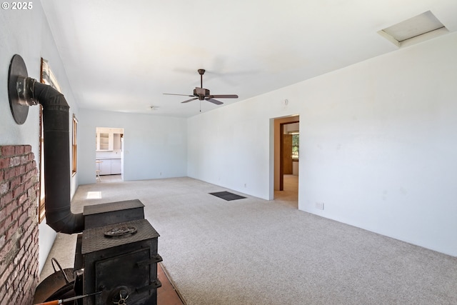 2170 Hubbard Creek Rd, Umpqua, OR 97486 - unfurnished living room with a wood stove, light colored carpet, a ceiling fan, and attic access