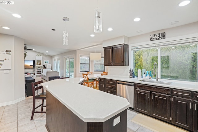 kitchen with decorative light fixtures, light countertops, stainless steel dishwasher, a kitchen island, and a sink