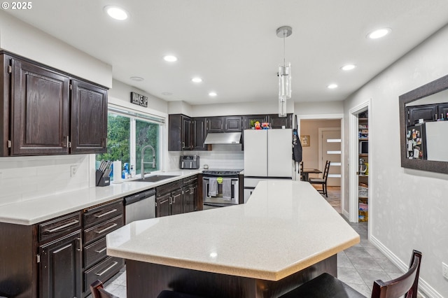 kitchen with a kitchen island, hanging light fixtures, stainless steel appliances, light countertops, and a sink