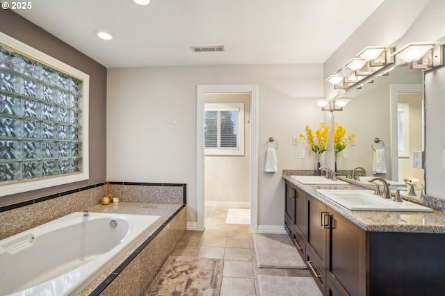 bathroom with tile patterned floors, vanity, and a relaxing tiled tub