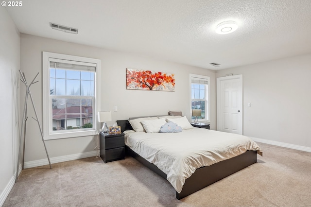 bedroom featuring baseboards, a textured ceiling, visible vents, and light colored carpet