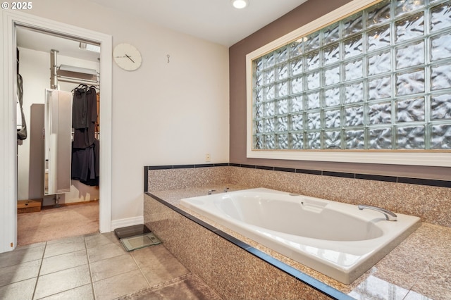 bathroom with tile patterned flooring, baseboards, a walk in closet, and a bath