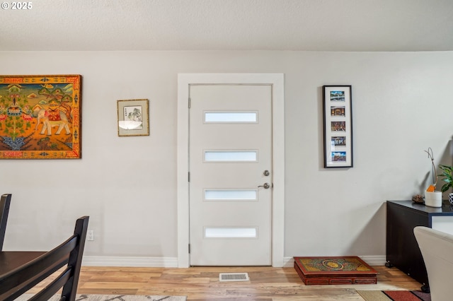 entryway with light wood-type flooring and a textured ceiling