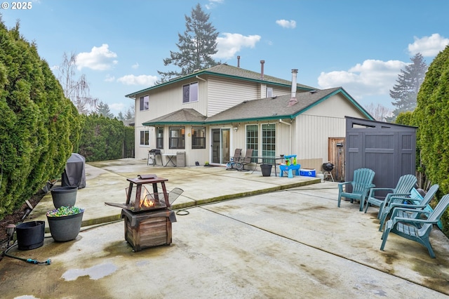 rear view of property with a fire pit, a patio, and a shingled roof