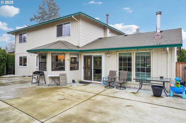 back of property with a patio, a shingled roof, and fence