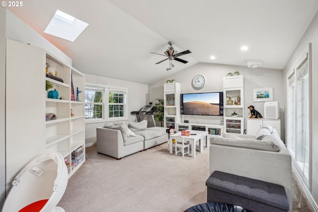 carpeted living room featuring vaulted ceiling with skylight and ceiling fan