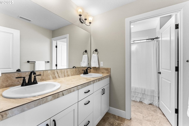 bathroom with visible vents, a sink, baseboards, and double vanity