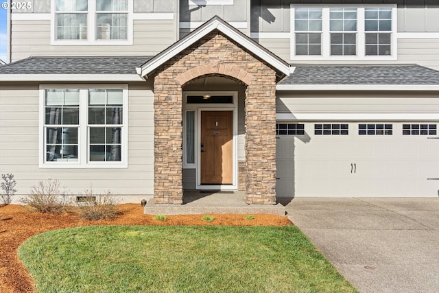 doorway to property featuring concrete driveway, stone siding, roof with shingles, crawl space, and an attached garage