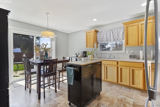 kitchen featuring a sink, light countertops, decorative light fixtures, and light brown cabinetry