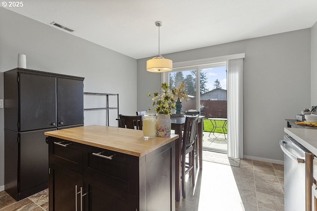 kitchen featuring baseboards, visible vents, butcher block countertops, hanging light fixtures, and stainless steel dishwasher