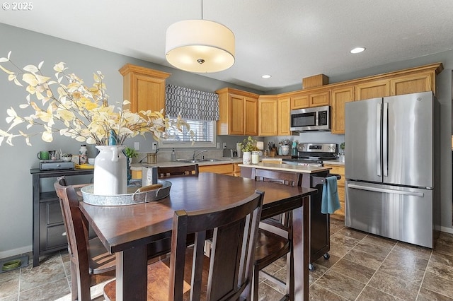 kitchen with baseboards, light countertops, recessed lighting, stainless steel appliances, and a sink