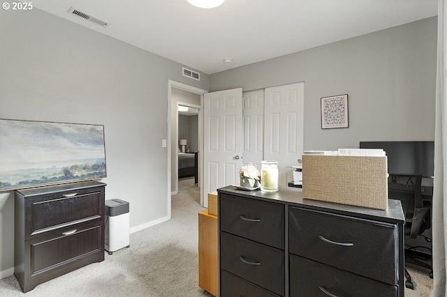 office space featuring baseboards, visible vents, and light carpet