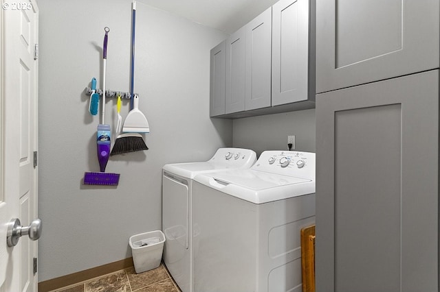 clothes washing area with washer and dryer, cabinet space, and baseboards