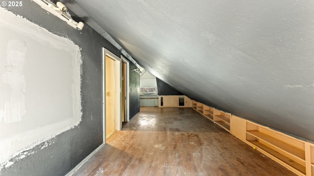 bonus room featuring vaulted ceiling, a textured ceiling, and wood finished floors