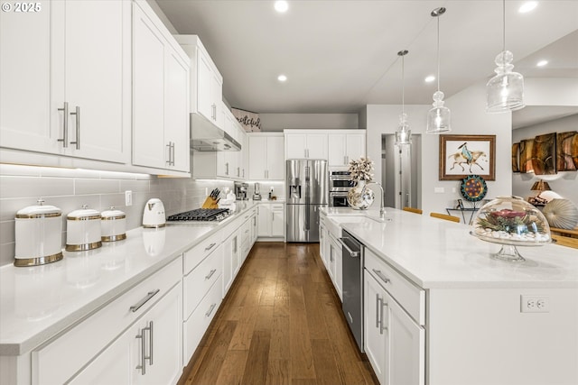 kitchen featuring backsplash, under cabinet range hood, light countertops, appliances with stainless steel finishes, and dark wood-style floors