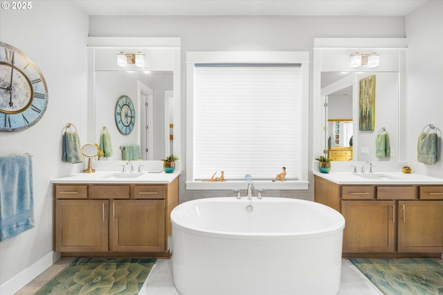 full bathroom featuring tile patterned floors, a freestanding tub, two vanities, and a sink