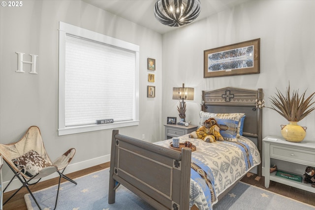 bedroom featuring a notable chandelier, baseboards, and wood finished floors