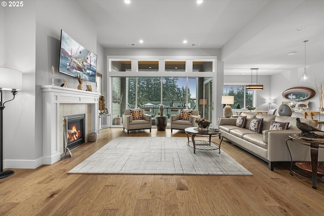 living room featuring visible vents, baseboards, a tiled fireplace, recessed lighting, and wood finished floors