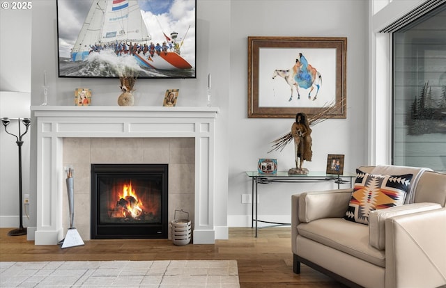 living area featuring wood finished floors, baseboards, and a tile fireplace