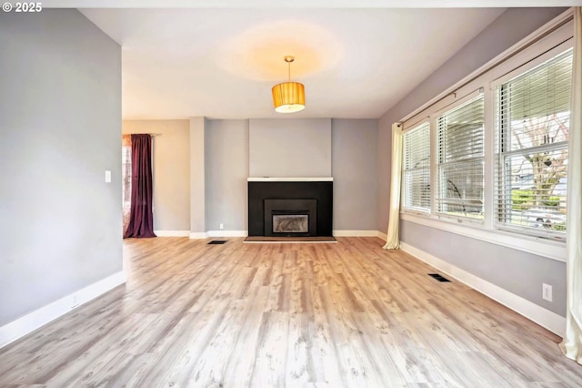 unfurnished living room featuring a fireplace, visible vents, baseboards, and light wood-type flooring