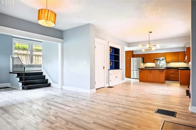 kitchen featuring visible vents, an inviting chandelier, freestanding refrigerator, dark countertops, and open floor plan