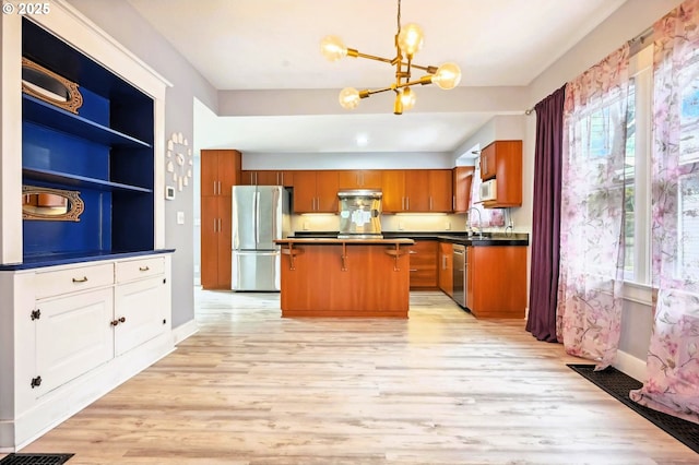 kitchen with brown cabinetry, a sink, appliances with stainless steel finishes, dark countertops, and a center island