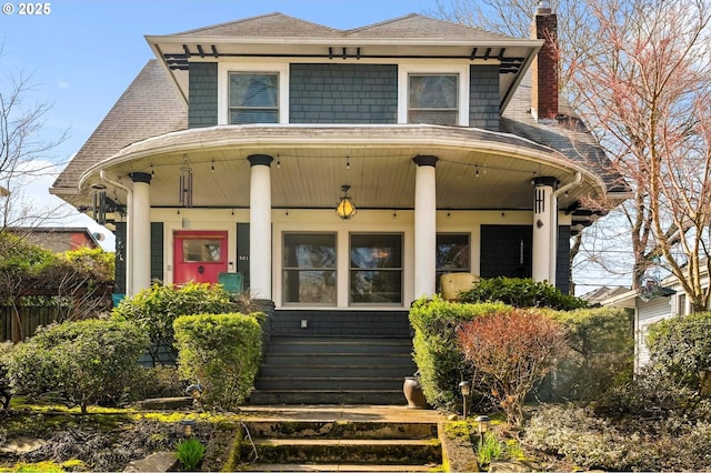 view of front of home featuring covered porch, a chimney, and roof with shingles