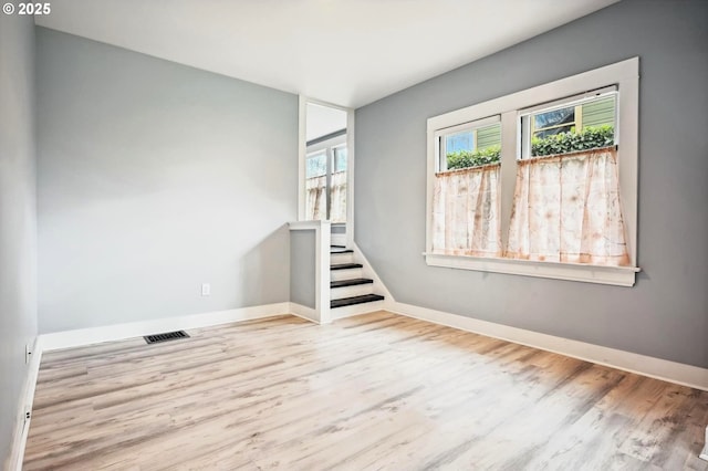 spare room with stairs, visible vents, wood finished floors, and baseboards