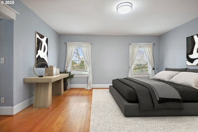 bedroom with multiple windows, baseboards, and light wood-style floors