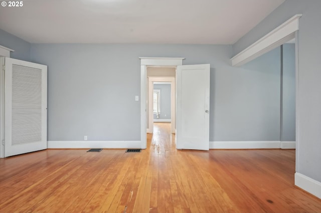 unfurnished room with visible vents, baseboards, and hardwood / wood-style flooring