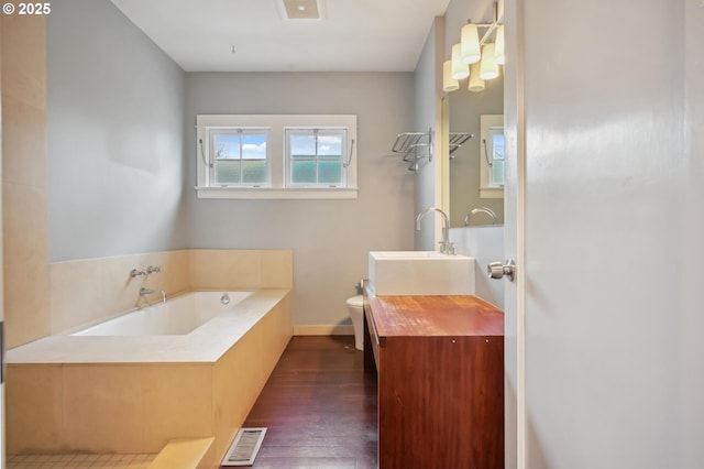 full bathroom with visible vents, a garden tub, toilet, wood finished floors, and vanity