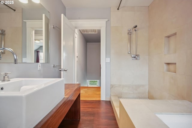 bathroom with vanity, wood finished floors, visible vents, and a tile shower