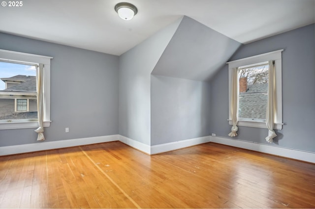 additional living space featuring light wood-style flooring, baseboards, and vaulted ceiling