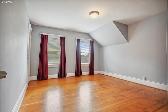 additional living space featuring vaulted ceiling, wood finished floors, and baseboards