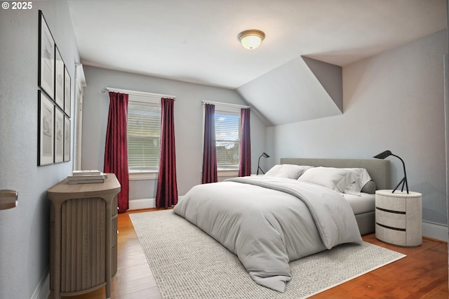 bedroom with lofted ceiling, wood finished floors, and baseboards