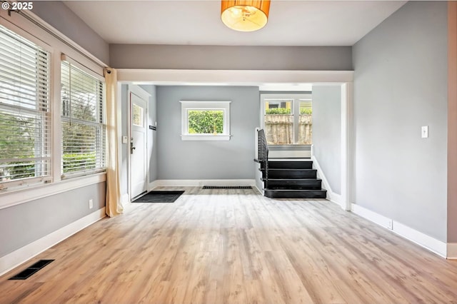 doorway featuring visible vents, light wood-style flooring, stairs, and baseboards