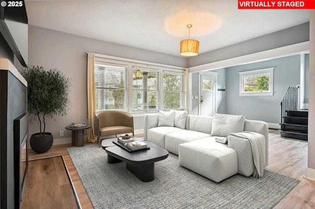 living room with stairway, baseboards, and wood finished floors