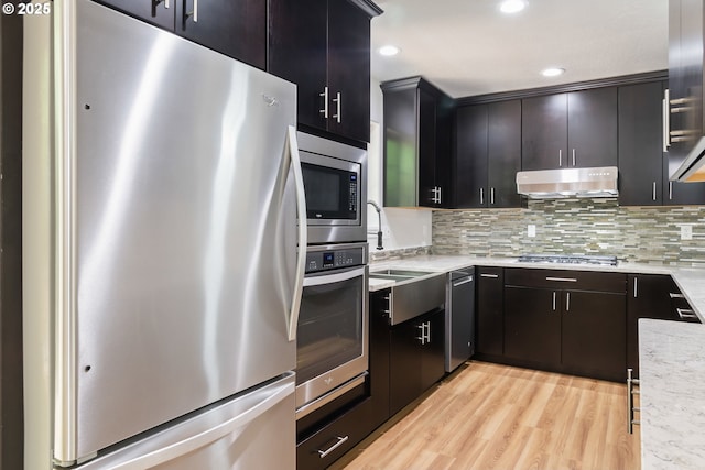 2795 Mallory Ln, Eugene, OR 97401 - kitchen featuring appliances with stainless steel finishes, under cabinet range hood, light wood-style floors, tasteful backsplash, and recessed lighting