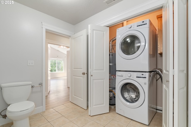 2795 Mallory Ln, Eugene, OR 97401 - washroom featuring stacked washer / drying machine, light tile patterned floors, baseboards, and gas water heater