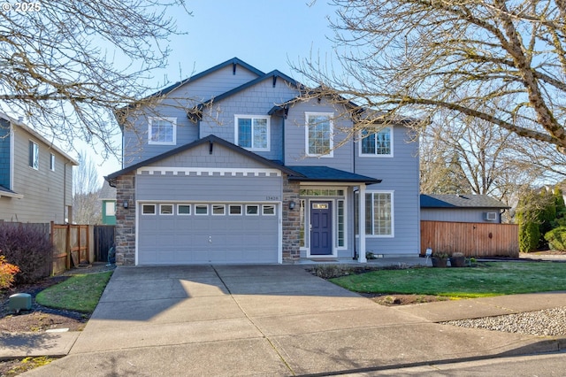 view of front facade with an attached garage, stone siding, driveway, and fence