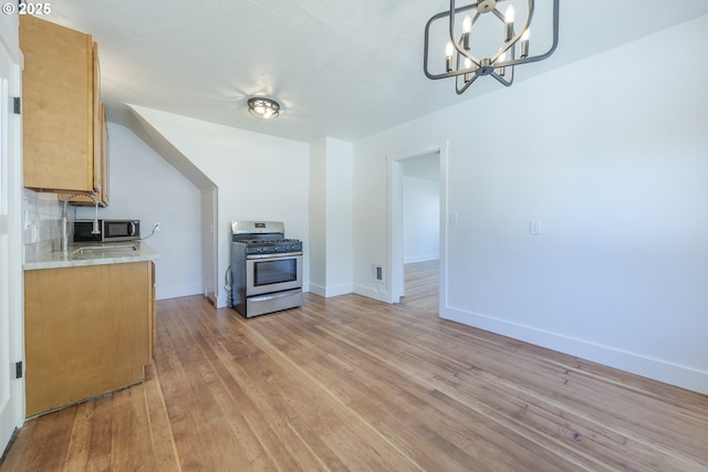 kitchen featuring appliances with stainless steel finishes, a chandelier, light countertops, light wood-style flooring, and baseboards