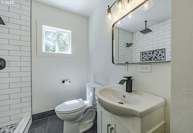 bathroom with a tile shower, vanity, toilet, and tile patterned floors
