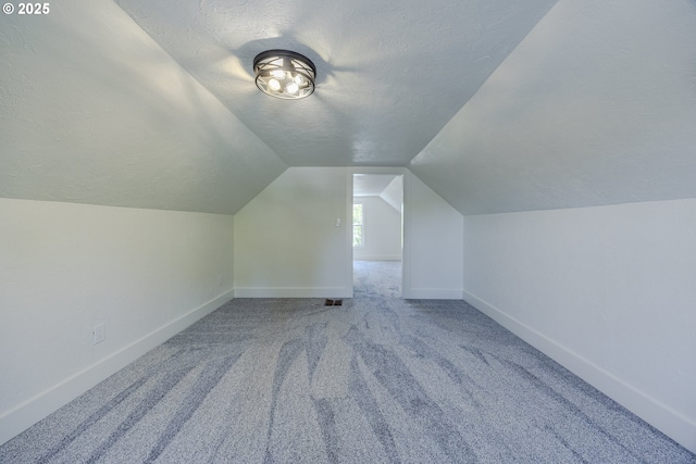 bonus room featuring vaulted ceiling, a textured ceiling, carpet floors, and baseboards
