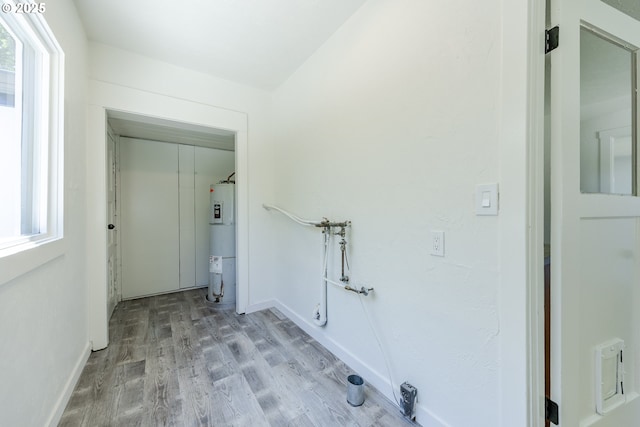 laundry area featuring water heater, wood finished floors, and baseboards