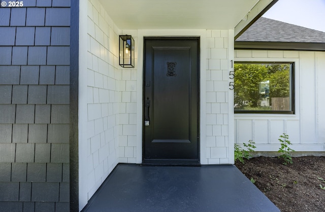 doorway to property featuring a shingled roof