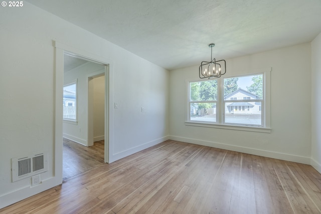 unfurnished dining area featuring a chandelier, light wood finished floors, and baseboards