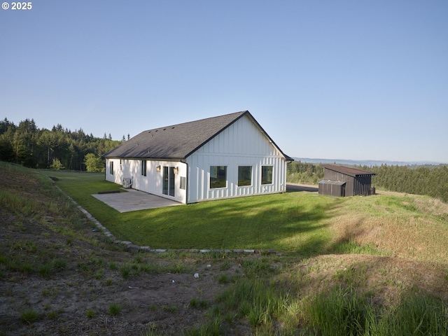 159 Bootjack Ln, Rose Valley, WA 98626 - back of property featuring board and batten siding, a lawn, a patio, and a shingled roof