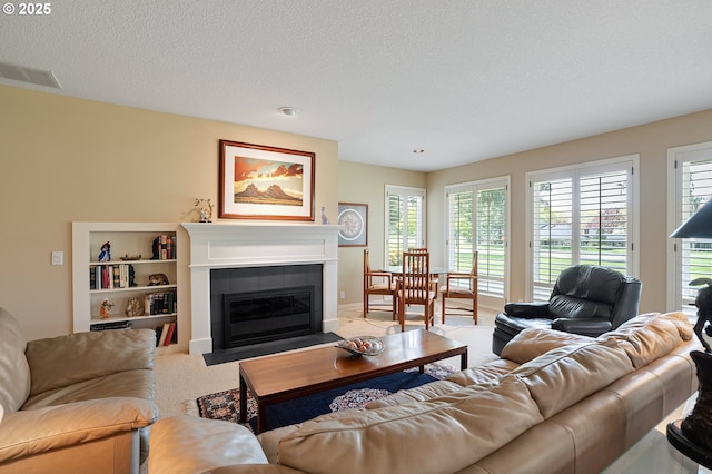 carpeted living room featuring a tile fireplace and a textured ceiling